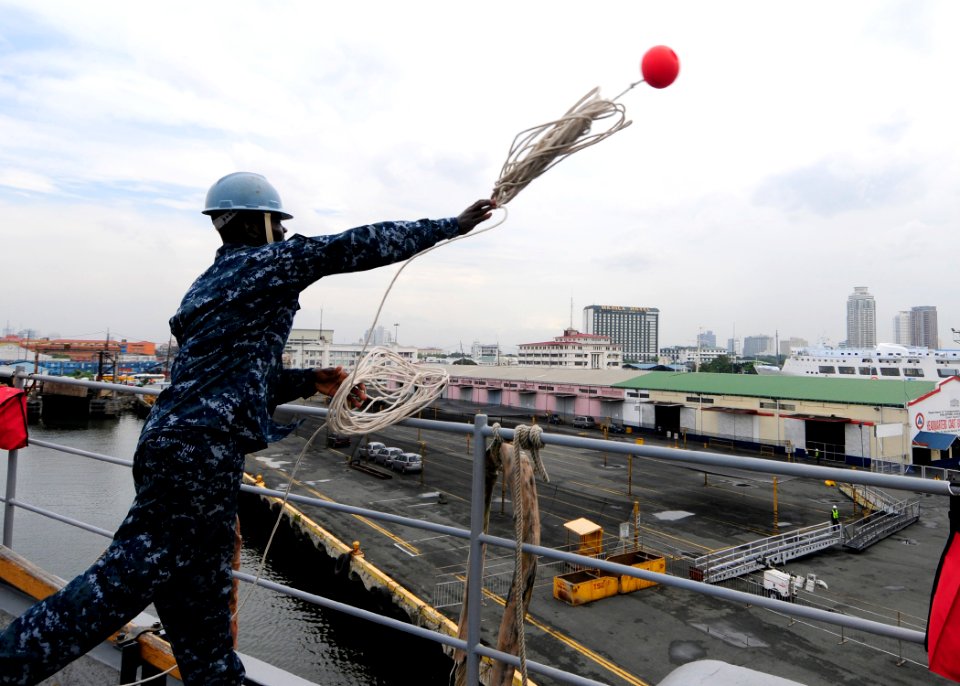 US Navy 111102-N-WJ771-084 Seaman Recruit Travis N. Abankwah throws a heaving line from the forecastle of the forward-deployed amphibious dock land