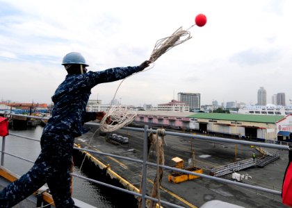 US Navy 111102-N-WJ771-084 Seaman Recruit Travis N. Abankwah throws a heaving line from the forecastle of the forward-deployed amphibious dock land