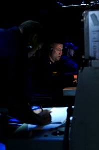 US Navy 111103-N-YM590-019 Chief Cryptologic Technician (Technical) Terry Draper, center, stands watch as the surface warfare coordinator in the Co