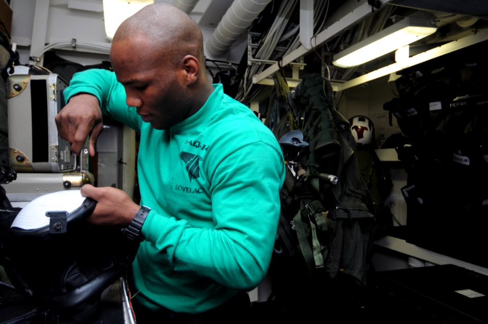 US Navy 111105-N-JD217-096 Aircrew Survival Equipmentman Airman Rashad C. Lovelace performs maintenance on a pilot's helmet aboard the aircraft car