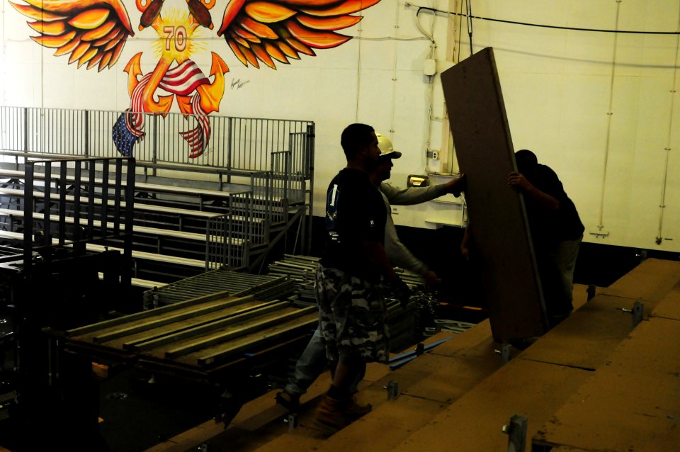 US Navy 111108-N-SB672-084 Civilian contractors raise the bleachers as workers prepare an alternate basketball arena in the hangar bay aboard the N