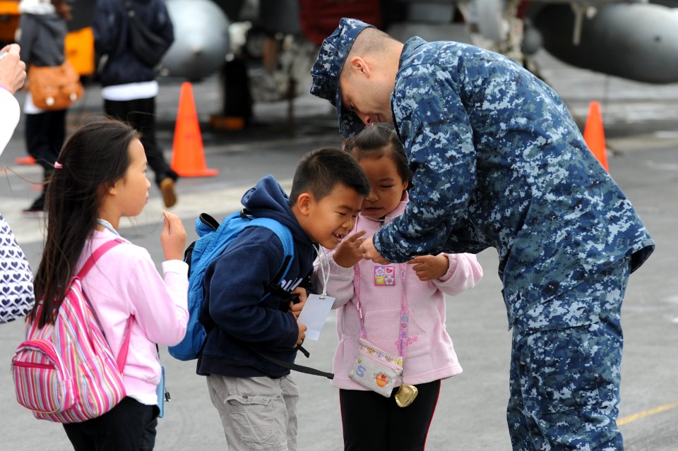 US Navy 111110-N-DS193-165 Lt. Cmdr. James Stockman speaks with children touring the aircraft carrier USS George Washington (CVN 73) during a port
