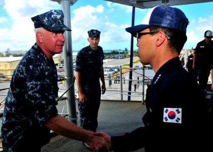US Navy 111107-N-BK435-001 Capt. Pete Hildreth, commanding officer of the submarine tender USS Frank Cable (AS 40), greets Lt. Kunwook Kang, operat