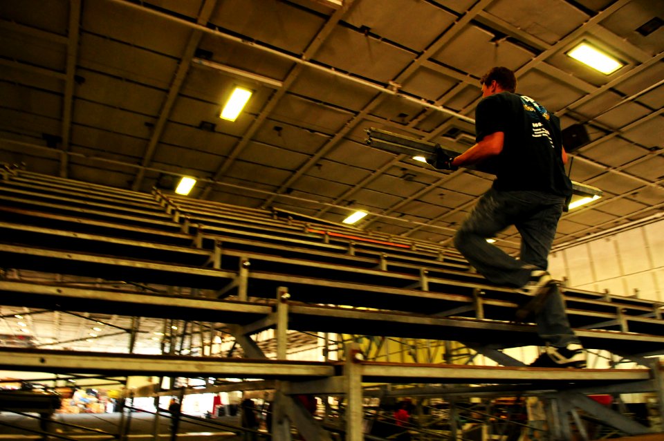 US Navy 111108-N-SB672-135 Civilian contractor Vadim Melline raises the bleachers as workers prepare an alternate basketball arena in the hangar b