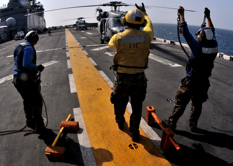 US Navy 111110-N-EC658-009 A landing signalman enlisted clears an MH-60S Sea Hawk helicopter for take off from the flight deck of the amphibious as
