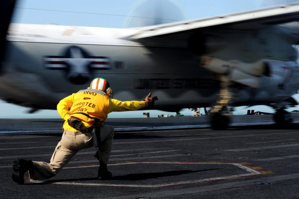 US Navy 111110-N-XE109-688 Lt. Scott Mckee signals to launch an E-2C Hawkeye, attached to Carrier Airborne Early Warning Squadron (VAW) 124, on the