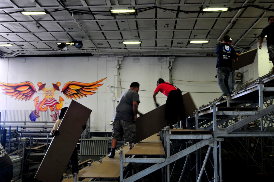 US Navy 111108-N-ZI635-183 Civilian contractors erect bleachers as workers construct an alternate basketball arena in the hangar bay aboard Nimitz