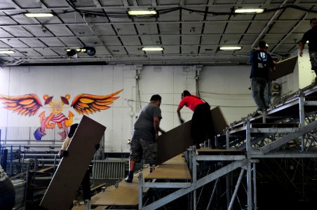 US Navy 111108-N-ZI635-183 Civilian contractors erect bleachers as workers construct an alternate basketball arena in the hangar bay aboard Nimitz