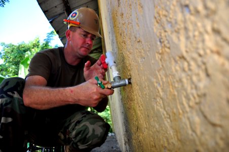 US Navy 111111-A-TF780-006 Utilitiesman 1st Class Bruce Nisbet fixes a faucet at the Iscuela Basica Rafaela Santaella school during a community ser