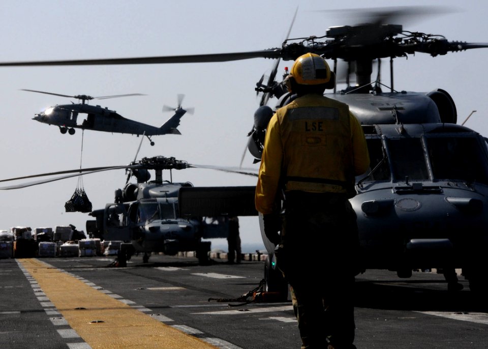 US Navy 111110-N-EC658-007 A landing signalman enlisted observes an MH-60S Sea Hawk helicopter approach the flight deck of the amphibious assault s