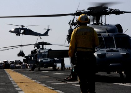 US Navy 111110-N-EC658-007 A landing signalman enlisted observes an MH-60S Sea Hawk helicopter approach the flight deck of the amphibious assault s