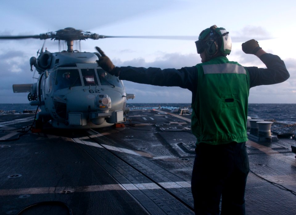 US Navy 111111-N-WX059-074 A sailor aboard the guided-missile destroyer USS Chafee (DDG 90) signals to the pilots of an SH-60B Sea Hawk helicopter