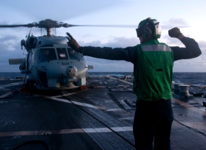 US Navy 111111-N-WX059-074 A sailor aboard the guided-missile destroyer USS Chafee (DDG 90) signals to the pilots of an SH-60B Sea Hawk helicopter