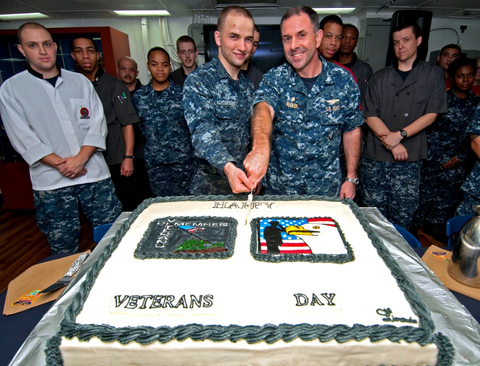 US Navy 111111-N-ER662-453 Seaman Peter Achterberg and Capt. David Fluker cut a cake during a Veterans Day celebration on the mess decks