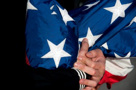 US Navy 111114-N-PB383-055 A Sailor assigned to the amphibious transport dock ship USS New Orleans (LPD 18) holds the national ensign for morning