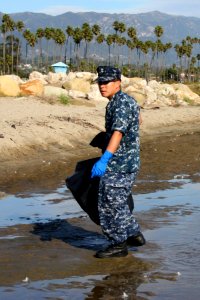 US Navy 111113-N-OM503-001 ire Controlman 2nd Class Duo Chen of Fort Lauderdale, Fla., searches for trash and debris during the community beach cle