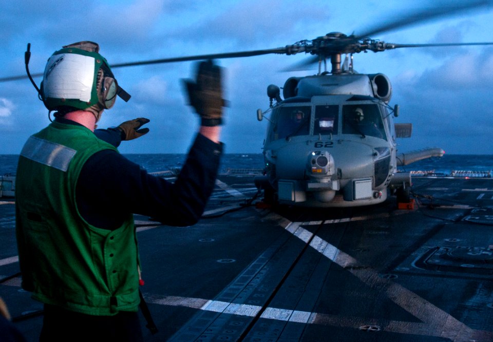 US Navy 111111-N-WX059-059 A sailor aboard the guided-missile destroyer USS Chafee (DDG 90) signals to the pilots of an SH-60B Sea Hawk helicopter