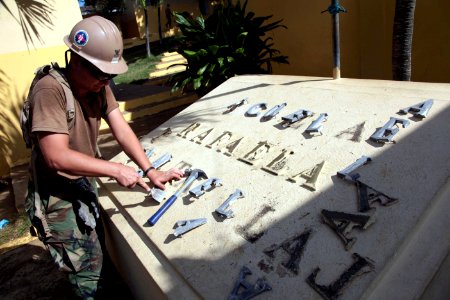 US Navy 111115-A-TF780-008 Heavy Equipment Operator 2nd Class Michael McAfee replaces letters on a monument bearing the name the school at Escuela