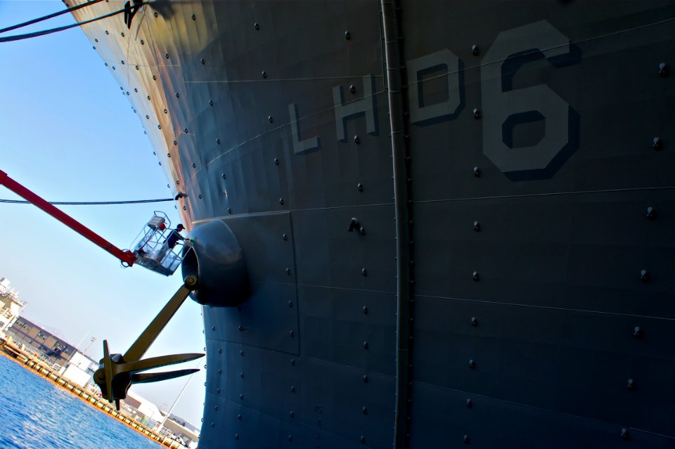 US Navy 111115-N-ZC343-797 Logistics Specialist Seaman Omar Borroto touches up the paint on the port anchor of the amphibious assault ship USS Bonh