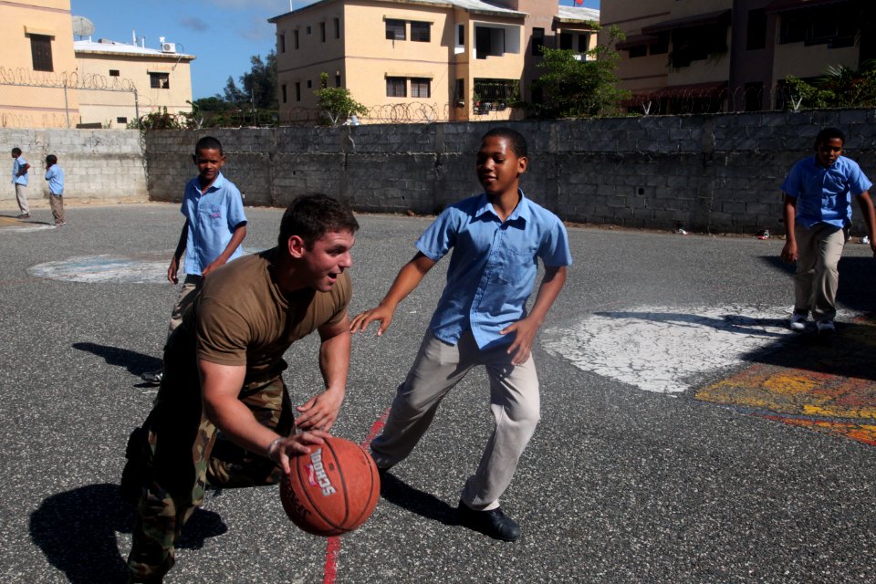 US Navy 111116-A-IP644-039 A Sailor attached to Navy Moblie Construction Battalion (NMCB) 23, dribbles past a Dominican boy during recess