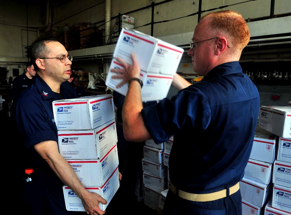 US Navy 111118-N-CT127-042 Command Master Chief Ryan Wagner passes care packages from the Adopt-a-Ship program to Hospital Corpsman 2nd Class Jason