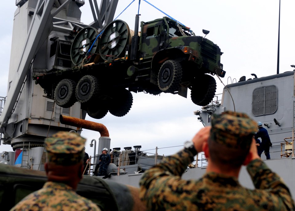 US Navy 111118-N-WJ771-256 Marines assigned to Combat Logistics Regiment 3 watch as a medium tactical vehicle replacement is loaded into the well d