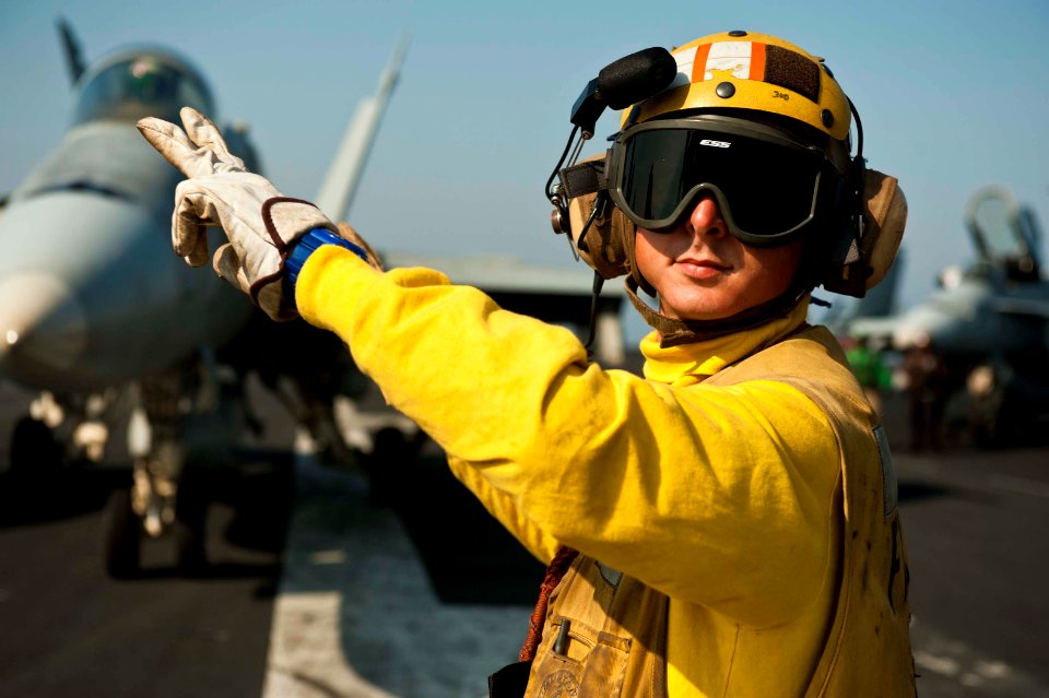 US Navy 111119-N-BT887-134 Aviation Boatswain's Mate (Handling) 2nd Class Adam Zimniak directs an F-A-18C Hornet assigned to the Golden Dragons