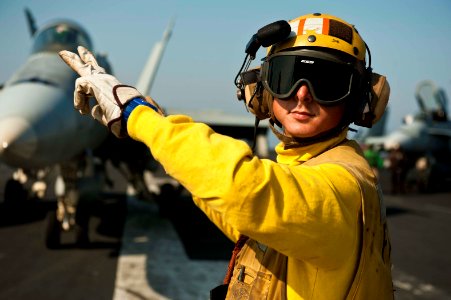 US Navy 111119-N-BT887-134 Aviation Boatswain's Mate (Handling) 2nd Class Adam Zimniak directs an F-A-18C Hornet assigned to the Golden Dragons