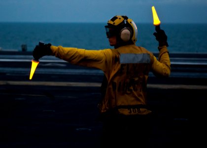US Navy 111121-N-BT887-048 Aviation Boatswain's Mate (Handling) Airman Michael Linscott directs fixed wing aircraft aboard the Nimitz-class aircraf