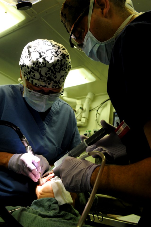US Navy 111116-N-QL471-060 Cmdr. Sandra M. Halterman, right, and Hospital Corpsman 2nd Class Adam J. Smolski perform an oral surgery aboard the air