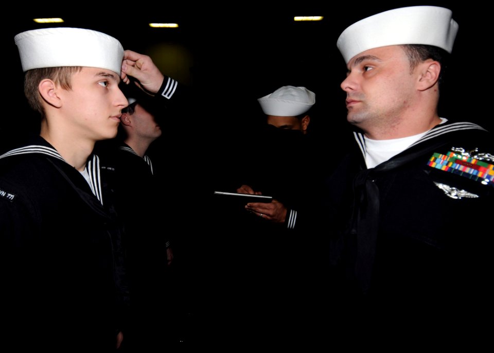 US Navy 111120-N-YC505-069 Electrician's Mate 1st Class Brian Odett inspects Electrician's Mate Fireman Cameron J. Herring's cover during a uniform