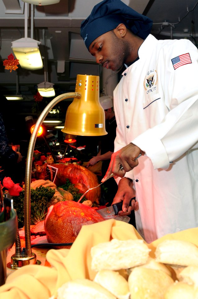 US Navy 111124-N-YC505-038 Culinary Specialist Seaman Aaron J. Hammond slices a ham on the mess decks aboard the aircraft carrier USS George H.W. B