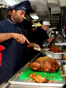 US Navy 111124-N-YC505-075 Culinary Specialist 2nd Class Charles Masten carves a turkey in a galley aboard the aircraft carrier USS George H.W. Bus