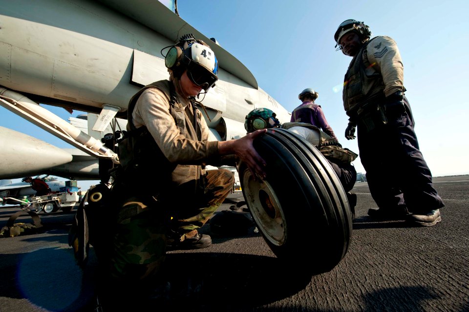 US Navy 111119-N-BT887-364 Aviation Machinist's Mate 2nd Class Catherine Clements inspects a tire before installing onto an F-A-18C Hornet