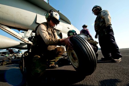 US Navy 111119-N-BT887-364 Aviation Machinist's Mate 2nd Class Catherine Clements inspects a tire before installing onto an F-A-18C Hornet