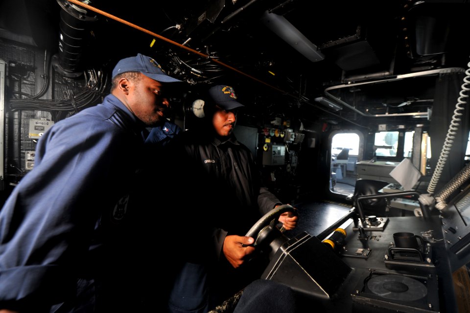 US Navy 111122-N-YZ751-085 Boatswain's Mate 1st Class Christian O. Giribaldi, right, demonstrates how to steer in rough seas to Boatswain's Mate 3r