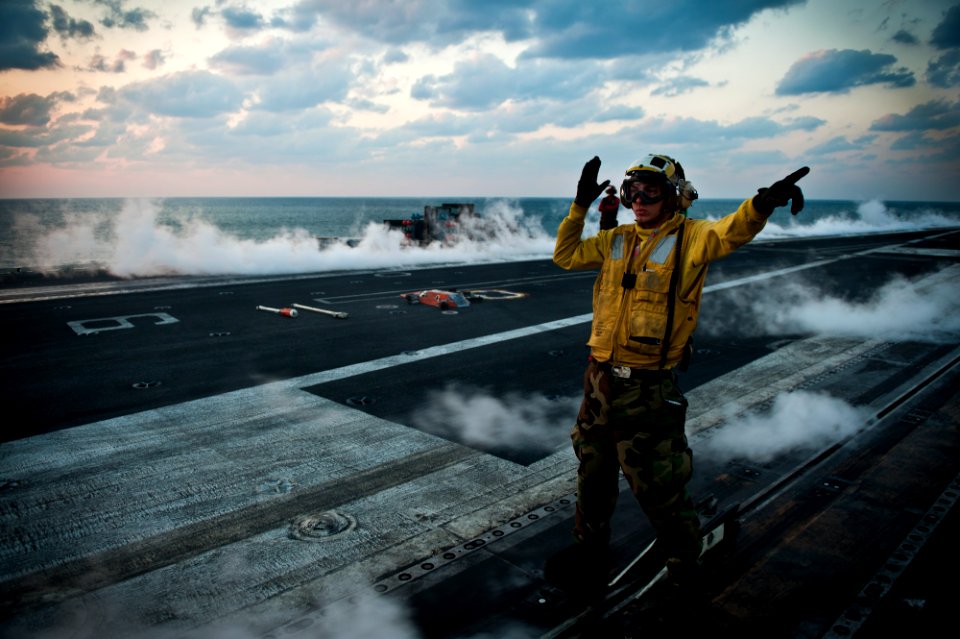 US Navy 111125-N-BT887-322 Aviation Boatswain's Mate (Handling) 3rd Class Eric Augustine directs aircraft aboard the Nimitz-class aircraft carrier