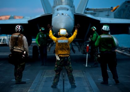US Navy 111121-N-BT887-036 Aviation Boatswain's Mate (Handling) Airman Michael Linscott directs an F-A-18F Super Hornet aboard the Nimitz-class air