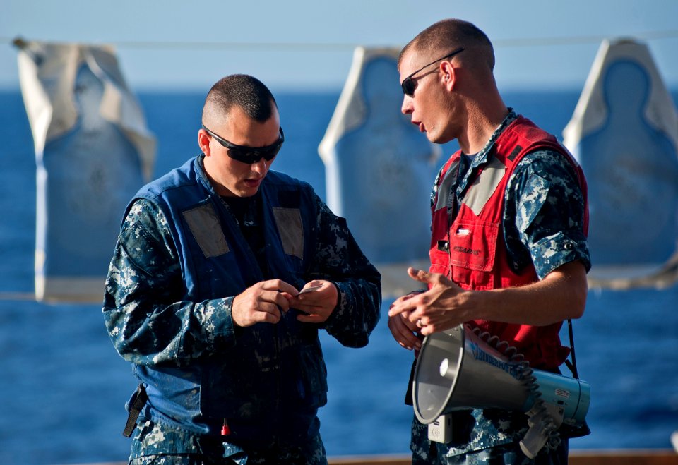 US Navy 111129-N-DX615-244 Operations Specialist 2nd Class Beau Barfield and Gunner's Mate 1st Class Joseph Abbott review procedures for a 9mm pist