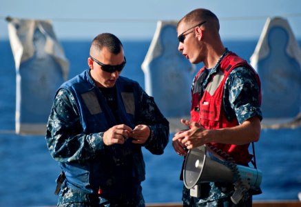 US Navy 111129-N-DX615-244 Operations Specialist 2nd Class Beau Barfield and Gunner's Mate 1st Class Joseph Abbott review procedures for a 9mm pist