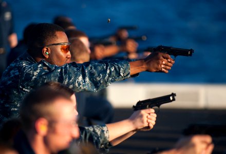 US Navy 111129-N-PB383-126 Yeoman 1st Class Kenneth Bradley aims his 9mm at his target from the kneeling position during small arms qualifications