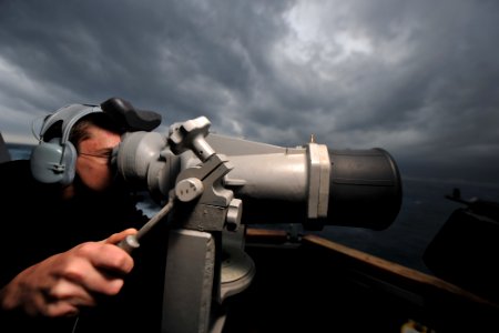 US Navy 111122-N-YZ751-101 Operations Specialist Seaman Anthony C. Tyrrell looks through the ship's big eyes on the bridge wing aboard the guided-m