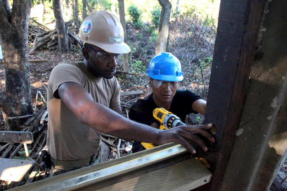 US Navy 111212-A-IP644-043 Equipment Operator 2nd Class Tyrif Wells applies aluminum side panels with Salvadoran Marine Neftan Patriz to a kitchen