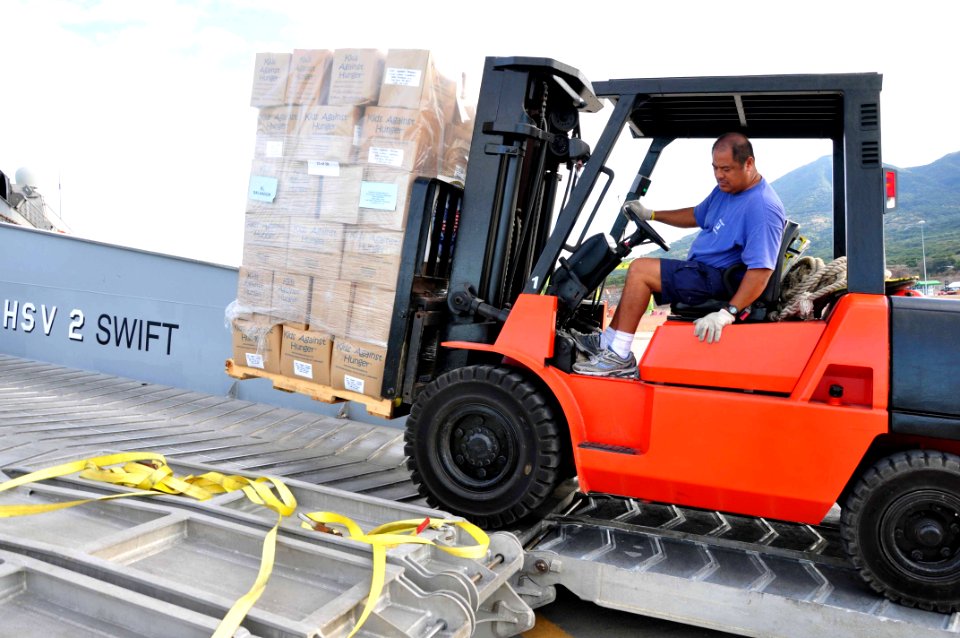 US Navy 111214-A-TF780-058 Reynolds Tinay, a civilian crew member assigned to High Speed Vessel (HSV 2) Swift, offloads pallets of goods for Projec