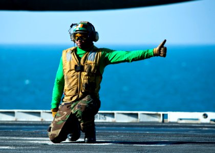 US Navy 111214-N-BT887-016 Aviation Boatswain's Mate (Equipment) 2nd Class Ashawn Robertson gives an approval to launch aircraft aboard the Nimitz photo