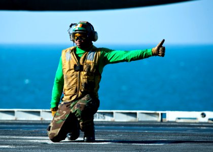 US Navy 111214-N-BT887-016 Aviation Boatswain's Mate (Equipment) 2nd Class Ashawn Robertson gives an approval to launch aircraft aboard the Nimitz