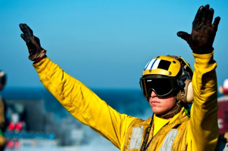 US Navy 111214-N-BT887-087 Aviation Boatswain's Mate (Handling) Airman Jarred Scifert directs aircraft aboard the Nimitz-class aircraft carrier USS