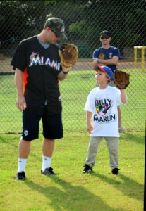 US Navy 111213-N-YU572-103 Miami Marlins catcher Brett Hayes shows the son of Naval Aircrewman 1st Class Scott Barrow how to hold a baseball mitt