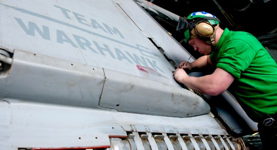 US Navy 111215-N-OY799-134 Aviation Structural Mechanic 3rd Class Stephen McGuiness removes clips on an F-A-18C Hornet aboard the Nimitz-class airc photo