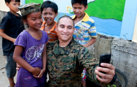 US Navy 111215-N-PB383-180 Sgt. Marcos Bustos poses for a photo with children during a community relation's event at the Help the Cambodian Childre